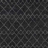 Close-up of the Sandyford Premium Rug. Black wool rug with a cream geometric diamond pattern. Hand-knotted texture. Swatch