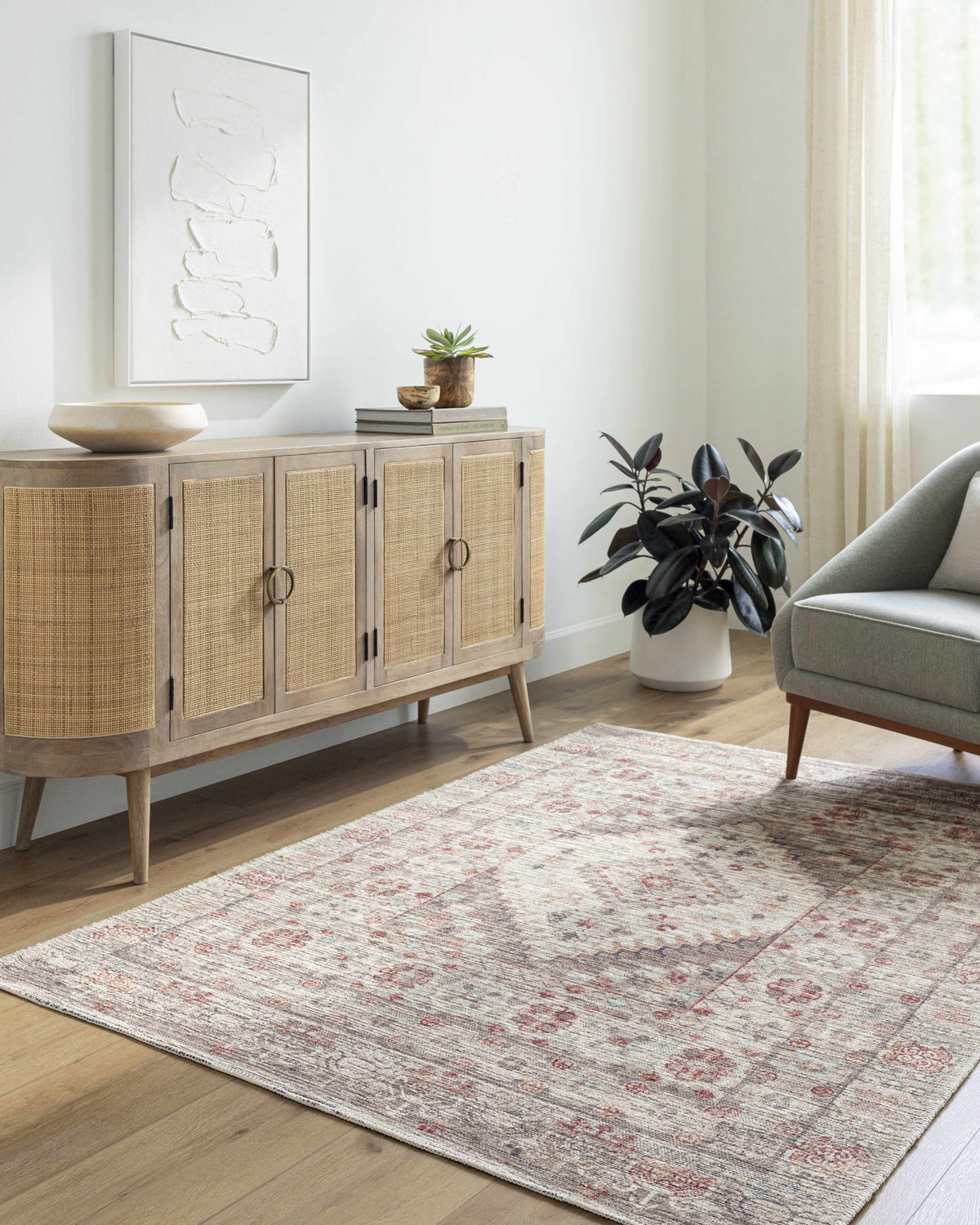 Living room scene with a neutral Liam Area Rug, wood cabinet, artwork, and gray chair. Farmhouse style. Roomscene-Rectangle