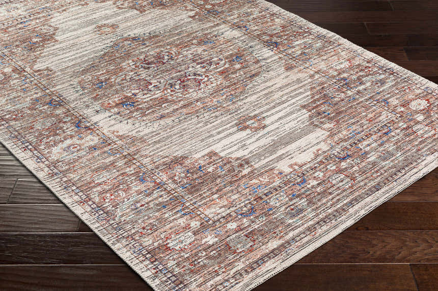 Close-up of the Maja Area Rug in beachhouse color, showcasing its traditional pattern and texture on a dark brown wood floor. Corner