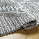 Close-up of the gray Edsel Area Rug showing its shag texture and geometric pattern on a wood floor. Fold