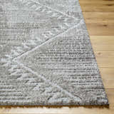 Close up of the Edsel Gray Area Rug showing its shag texture and geometric pattern on wood floor. Front