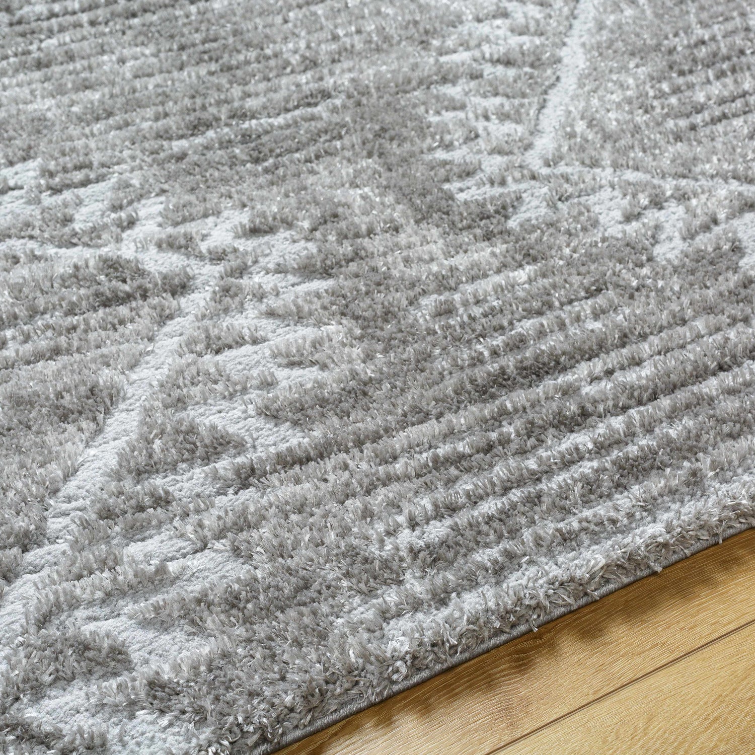 Close-up of the gray Edsel Area Rug showing its shag texture and subtle geometric pattern on hardwood floor. Texture