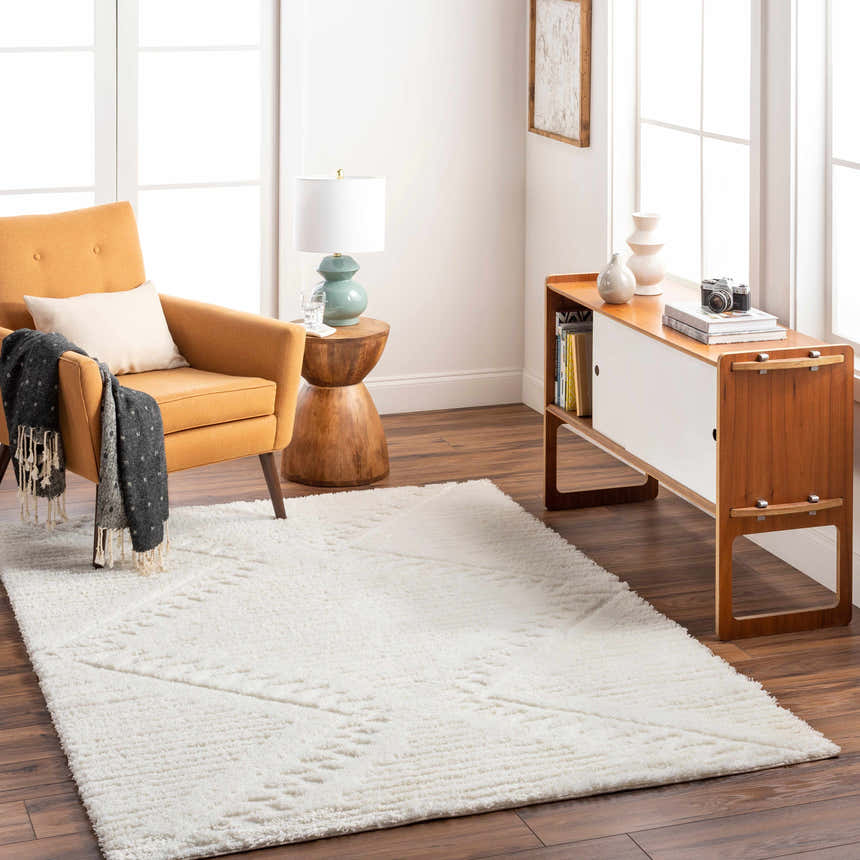 Living room scene with the Edsel Off-White Area Rug, mustard chair, wood cabinet, and hardwood floors. Bright, airy, and modern. Roomscene-Rectangle