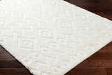 Close-up of the plush, white Hoshi Area Rug with a geometric shag design on dark wood flooring. Corner