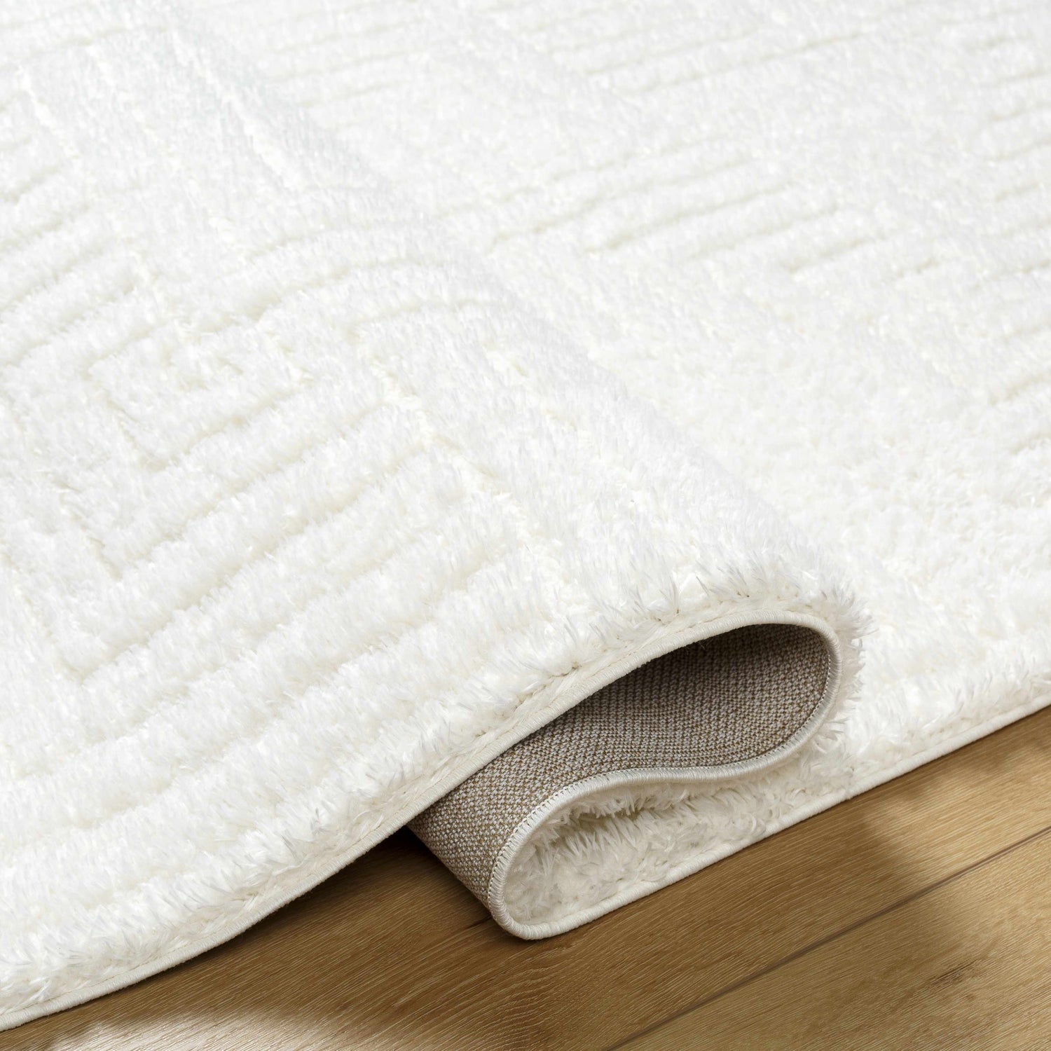 Close up of the ivory Layla Area Rug showing its shag texture and geometric pattern. Fold