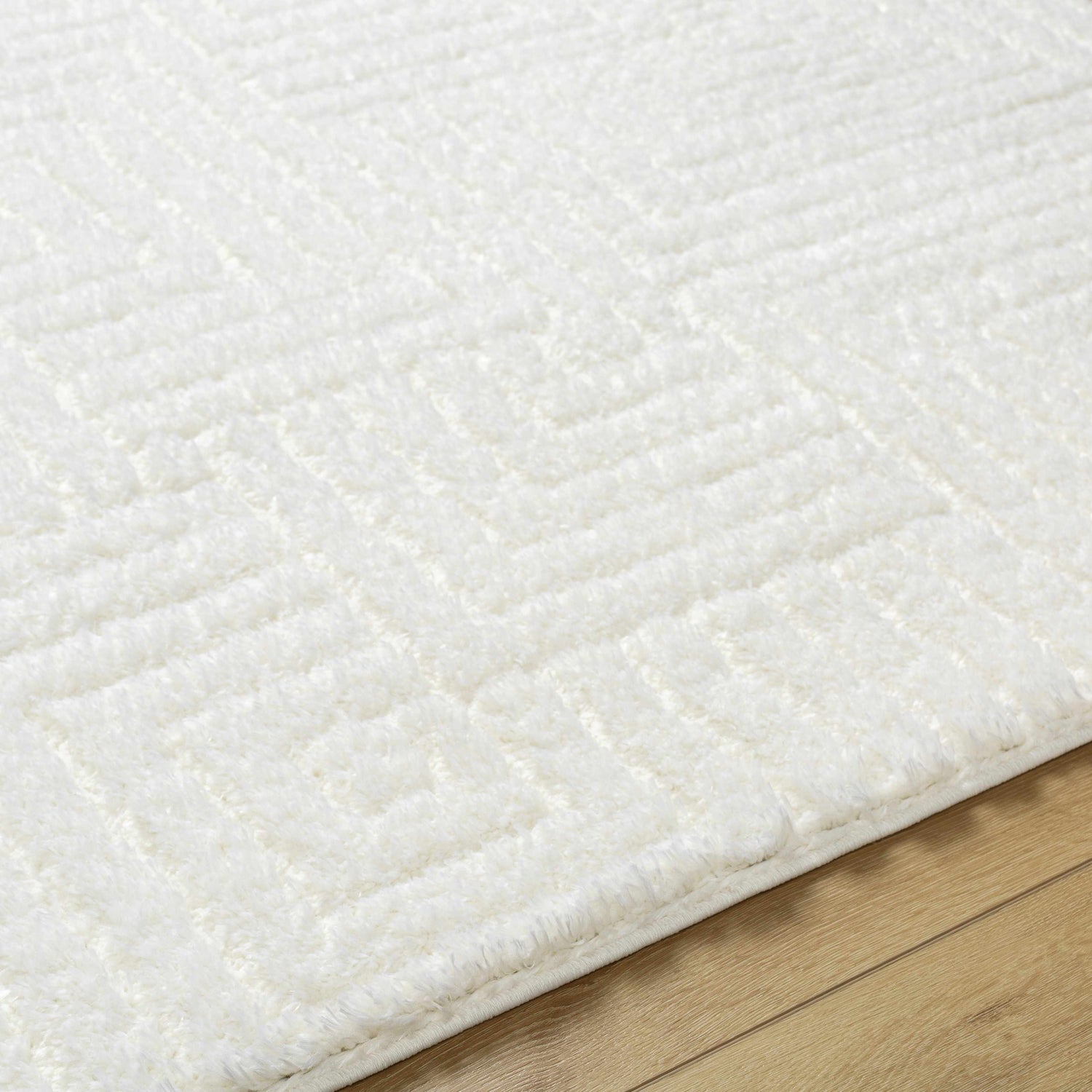 Close up of the Layla Area Rug. This shag rug has a geometric pattern and is white. Texture