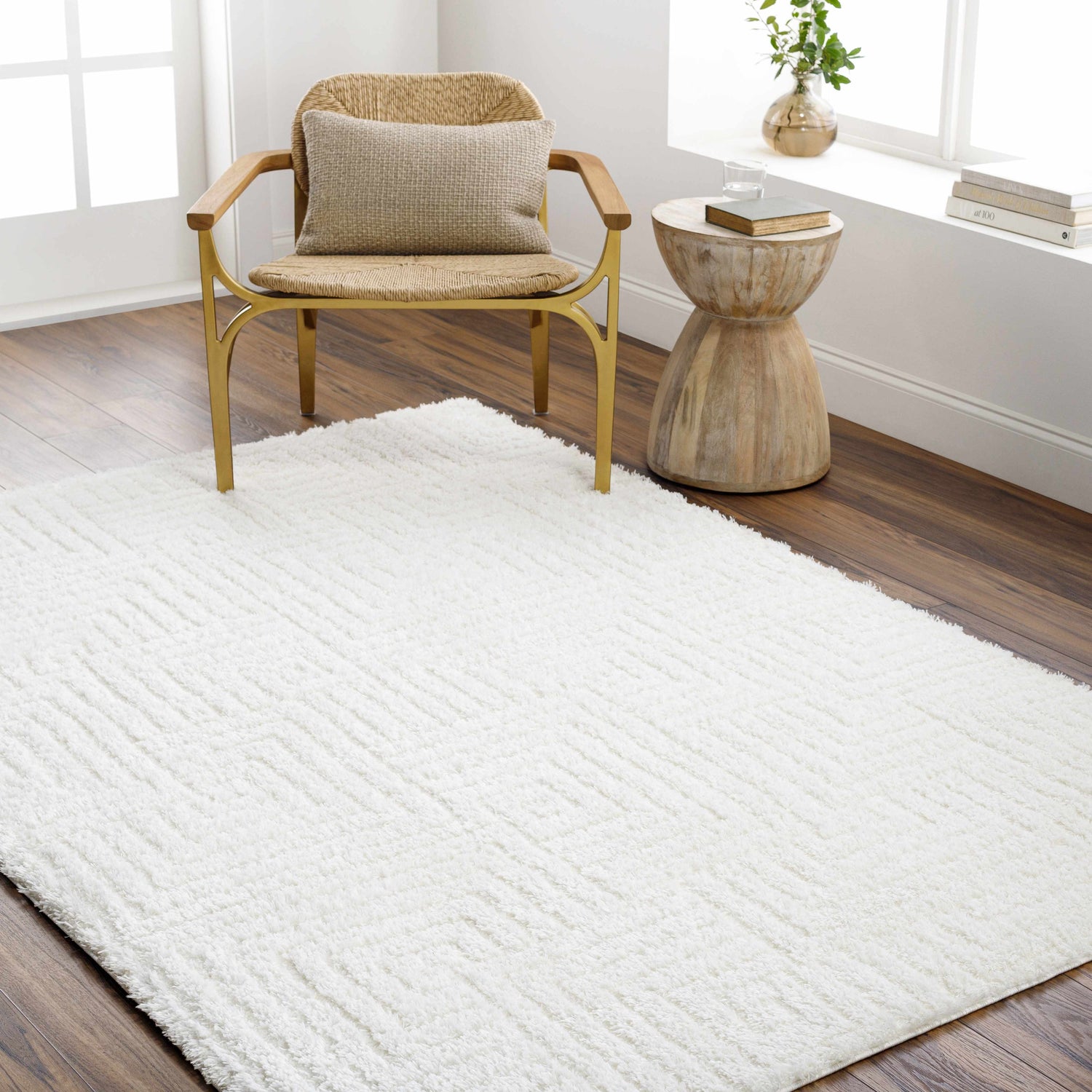 Bright room scene with a white Layla area rug, woven chair, wood side table, and dark wood floors. Roomscene-Rectangle