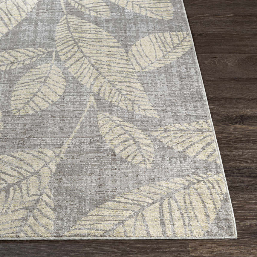 Close-up of the Snook Area Rug, showing a beige leaf pattern on a gray background, machine woven texture. Front