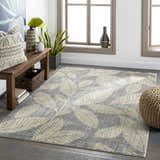 Living room scene with a gray Snook Area Rug featuring a beige leaf pattern, wood bench, and natural light. Roomscene-Rectangle