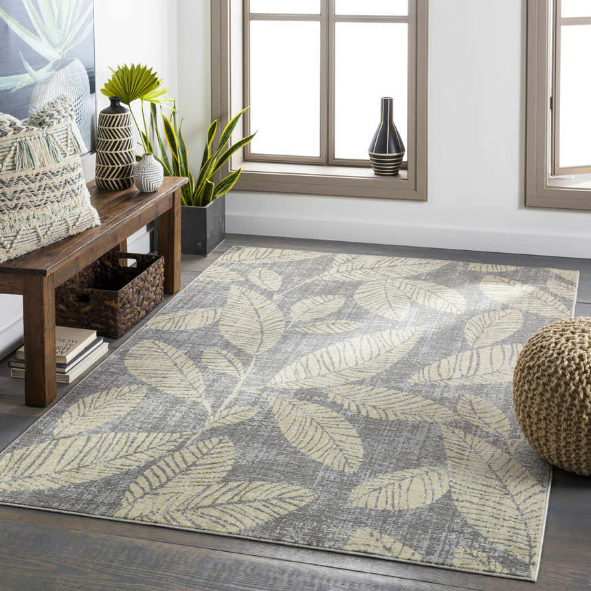 Living room scene with a gray Snook Area Rug featuring a beige leaf pattern, wood bench, and natural light. Roomscene-Rectangle