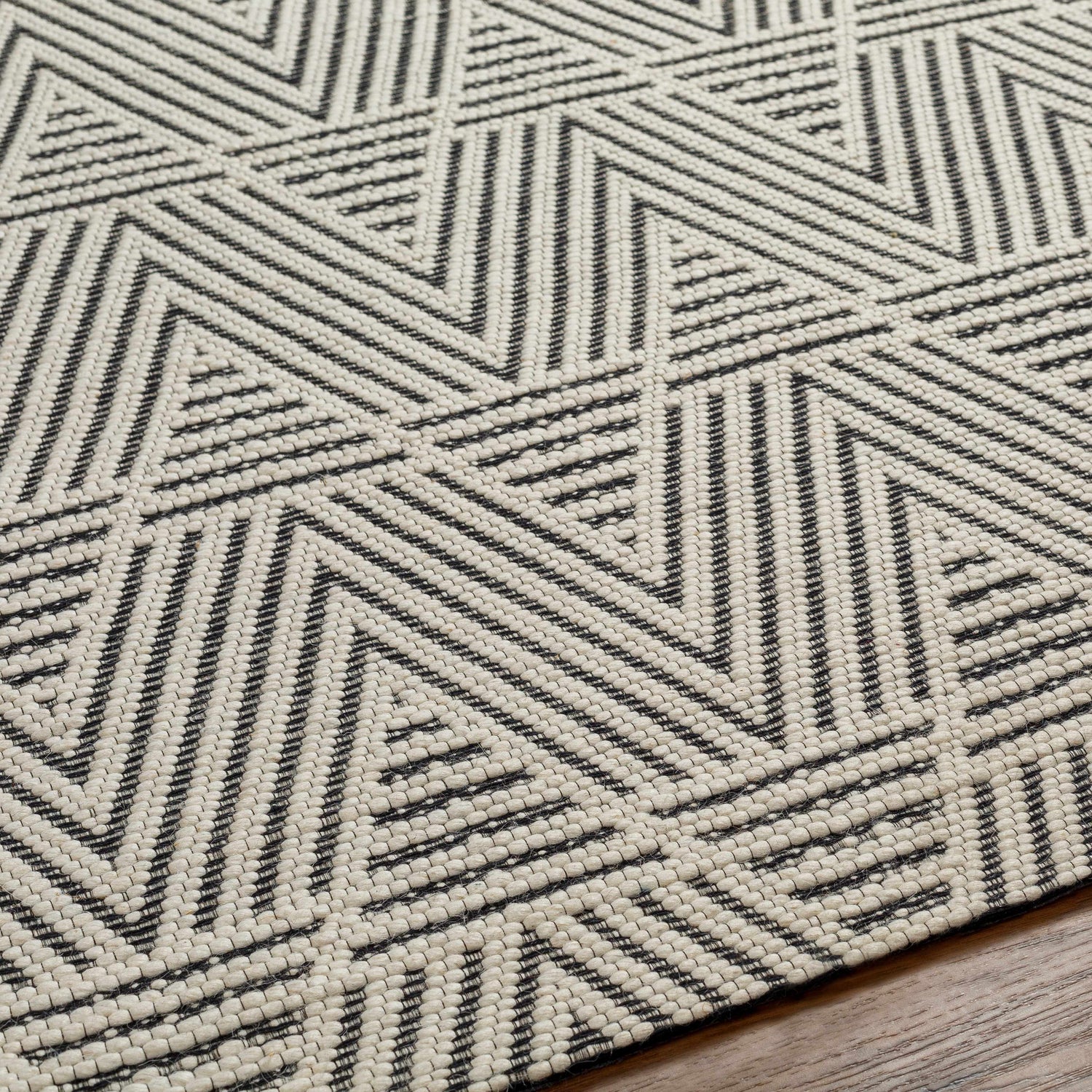 Close up of the Dawid Wool Area Rug featuring a black and bone geometric pattern. Texture