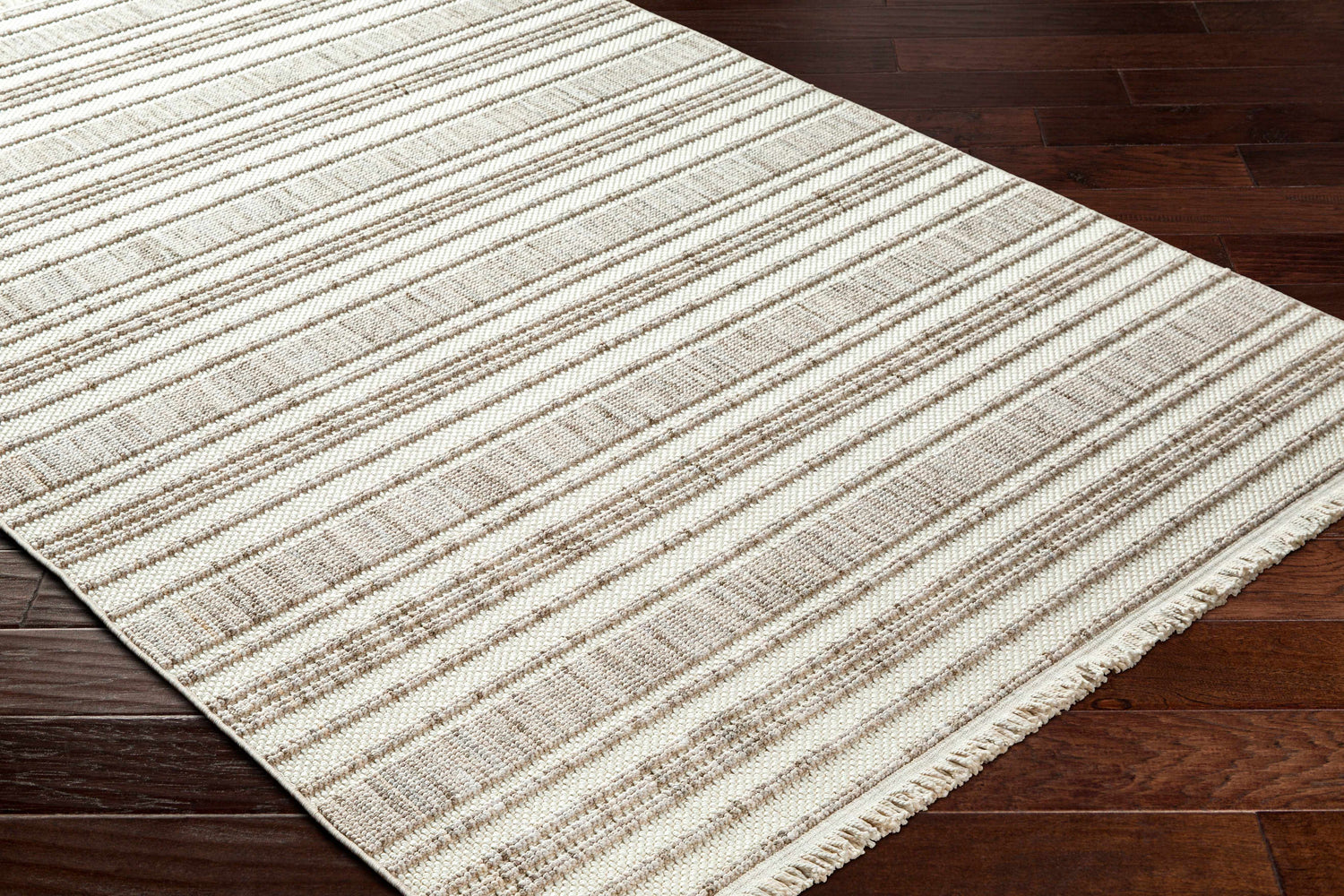 Close-up of the Avari Area Rug showing a striped pattern in beige and brown on dark wood floors. Corner
