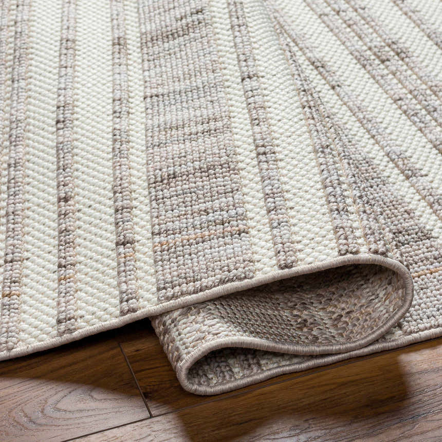 Close-up of the Avari Area Rug showing its beige, bone, and gray striped pattern and textured, machine-woven construction. Fold