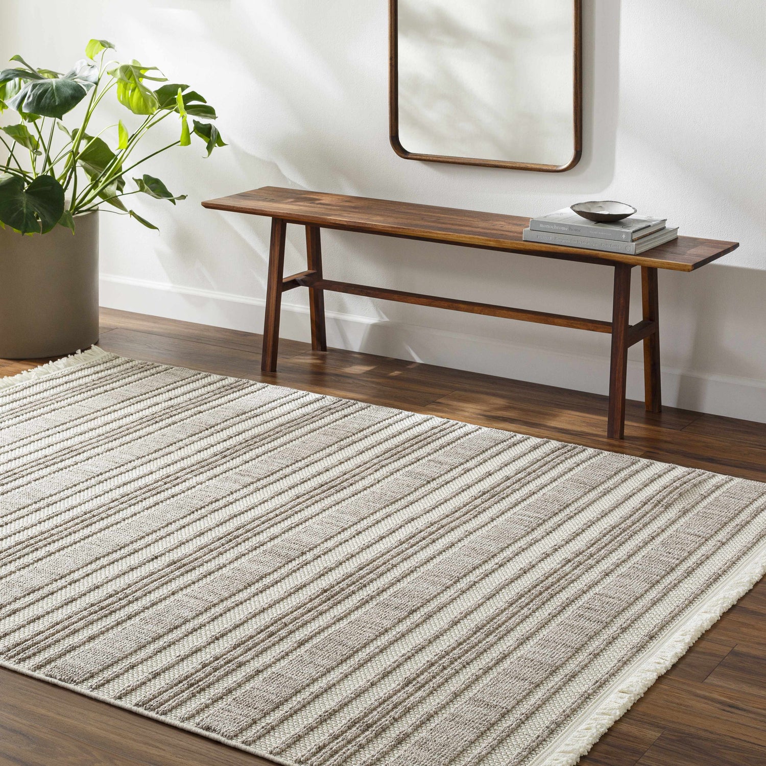 Entryway with Avari Area Rug in beige stripes, wood bench, mirror, and potted plant. Roomscene-Rectangle