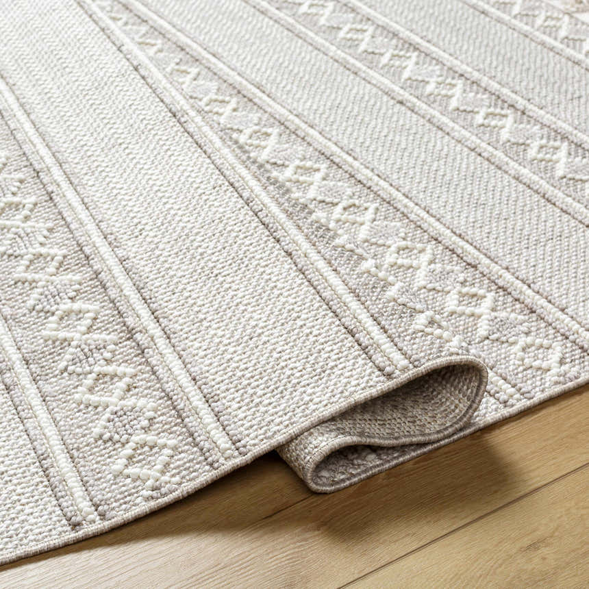 Close-up of the Dagan Area Rug showing its beige, gray, and cream geometric pattern and textured weave. Fold