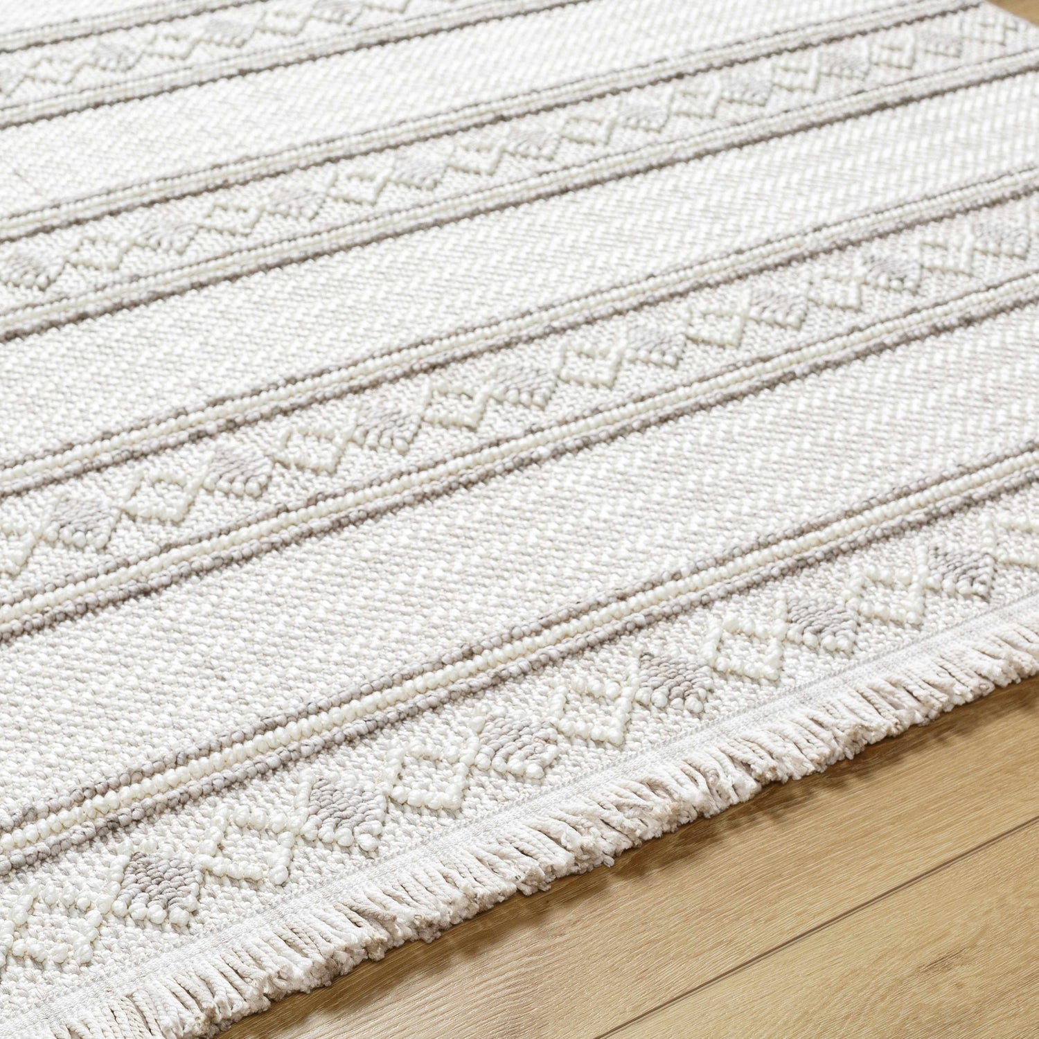 Close-up of the Dagan Area Rug showing beige, gray stripes, geometric patterns, fringe detail, and textured polyester weave. Texture