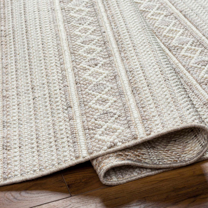 Close-up of the Dagan Area Rug showing its beige, gray, and cream textured weave and geometric pattern. Fold