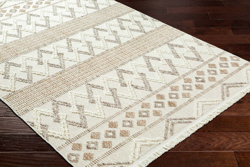 Close-up of the Faruq Area Rug showing a geometric pattern in beige, bone, and brown on dark wood flooring. Corner