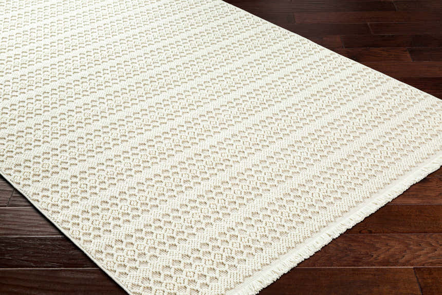 Close-up of the Hamal Area Rug showing its cloud gray and cream geometric pattern and textured weave on dark wood floor. Corner