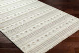 Close-up of the Hideo Area Rug showing its beige, gray, and brown geometric pattern and woven texture on dark wood floors. Corner