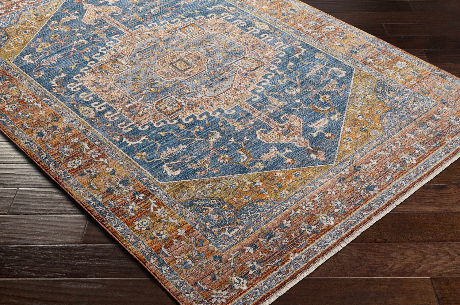 Close-up of Solana Blue Medallion Area Carpet showing its traditional, bohemian pattern and brick red, blue, and mustard colors. Corner