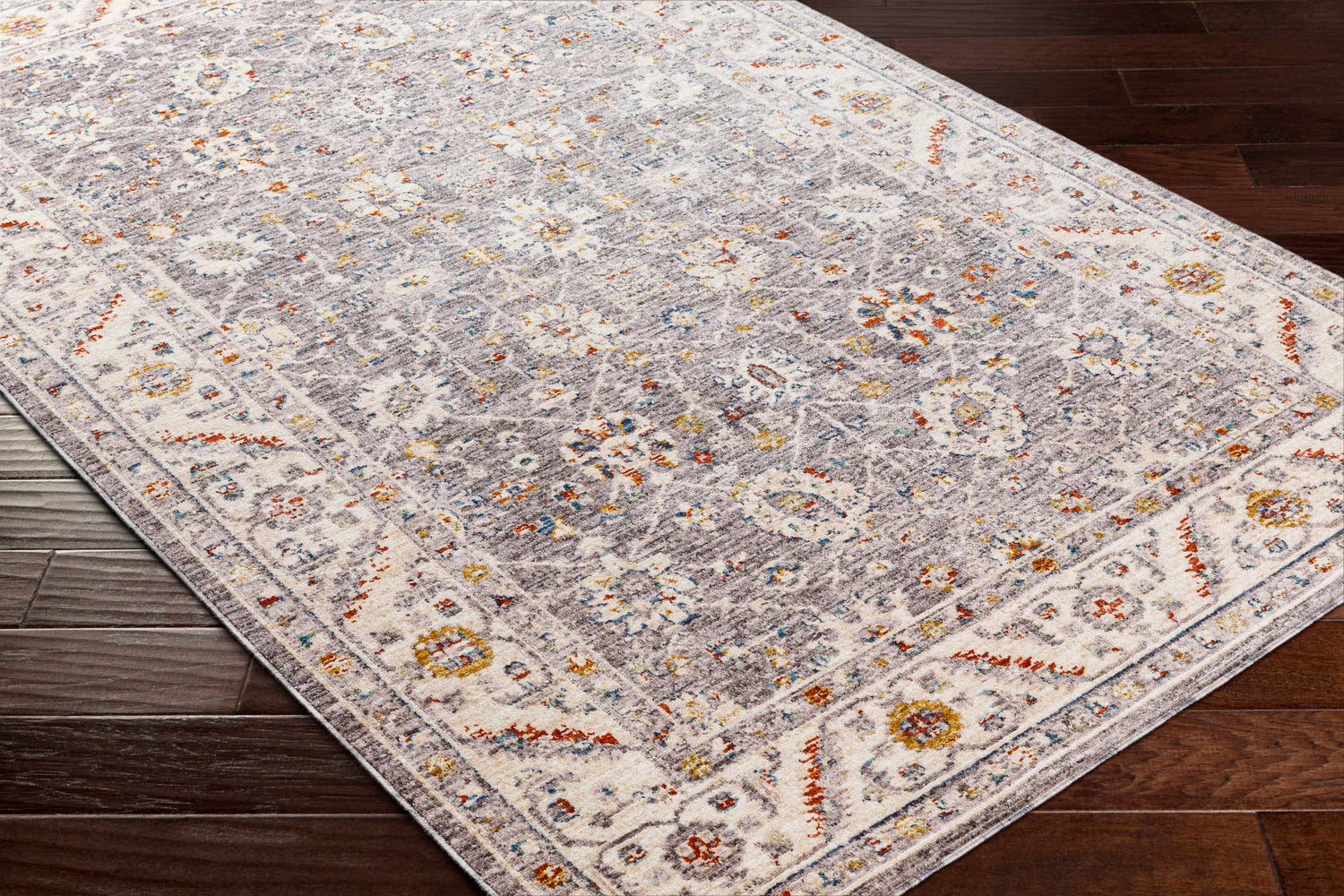 Close-up of the Sosi Area Carpet in dark beige, garnet, and gray on a dark wood floor. Traditional, farmhouse style. Corner