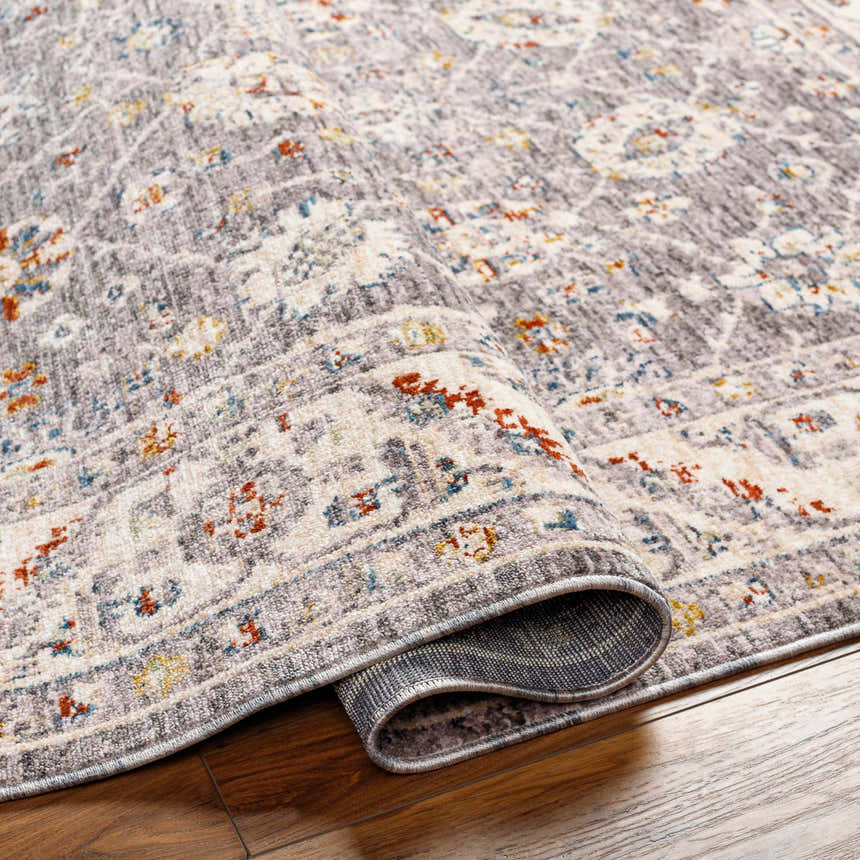 Close-up of the Sosi Area Carpet, a machine-woven rug in dark beige, garnet, gray, and taupe with a traditional pattern. Fold
