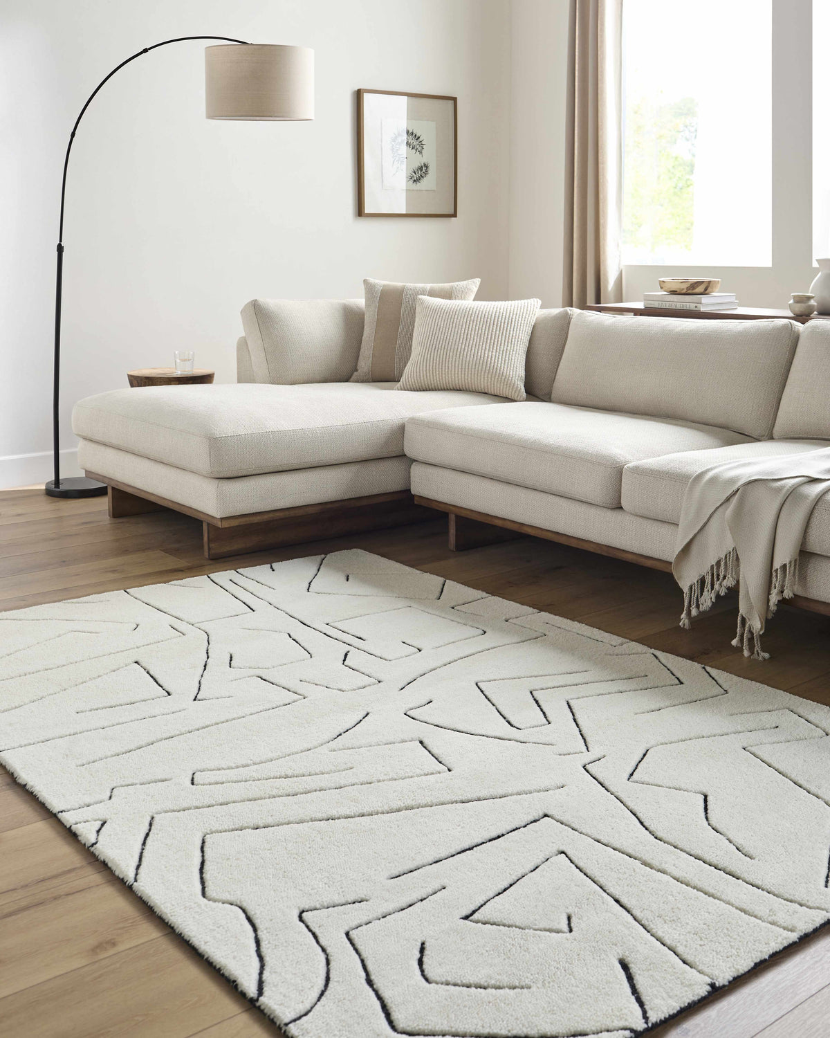 Living room with cream sectional sofa and Mony Rose Cream Area Rug with black geometric design. Roomscene-Rectangle