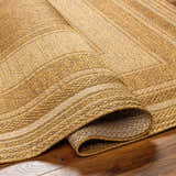 Close-up of the Chael Flatweave Faux Jute Rug showing beige, brown, and tan woven texture and rolled edge detail. Fold