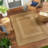 Outdoor patio scene with a beige Chael Flatweave Faux Jute Rug, wicker chairs, and potted plants on a wood deck. Roomscene-Rectangle