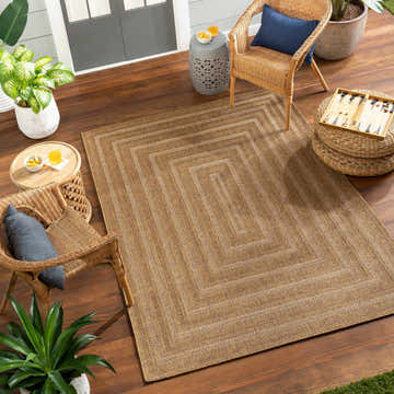 Outdoor patio scene with a camel Dyami Flatweave Faux Jute Rug, wicker chairs, and potted plants on a wood deck. Roomscene-Rectangle