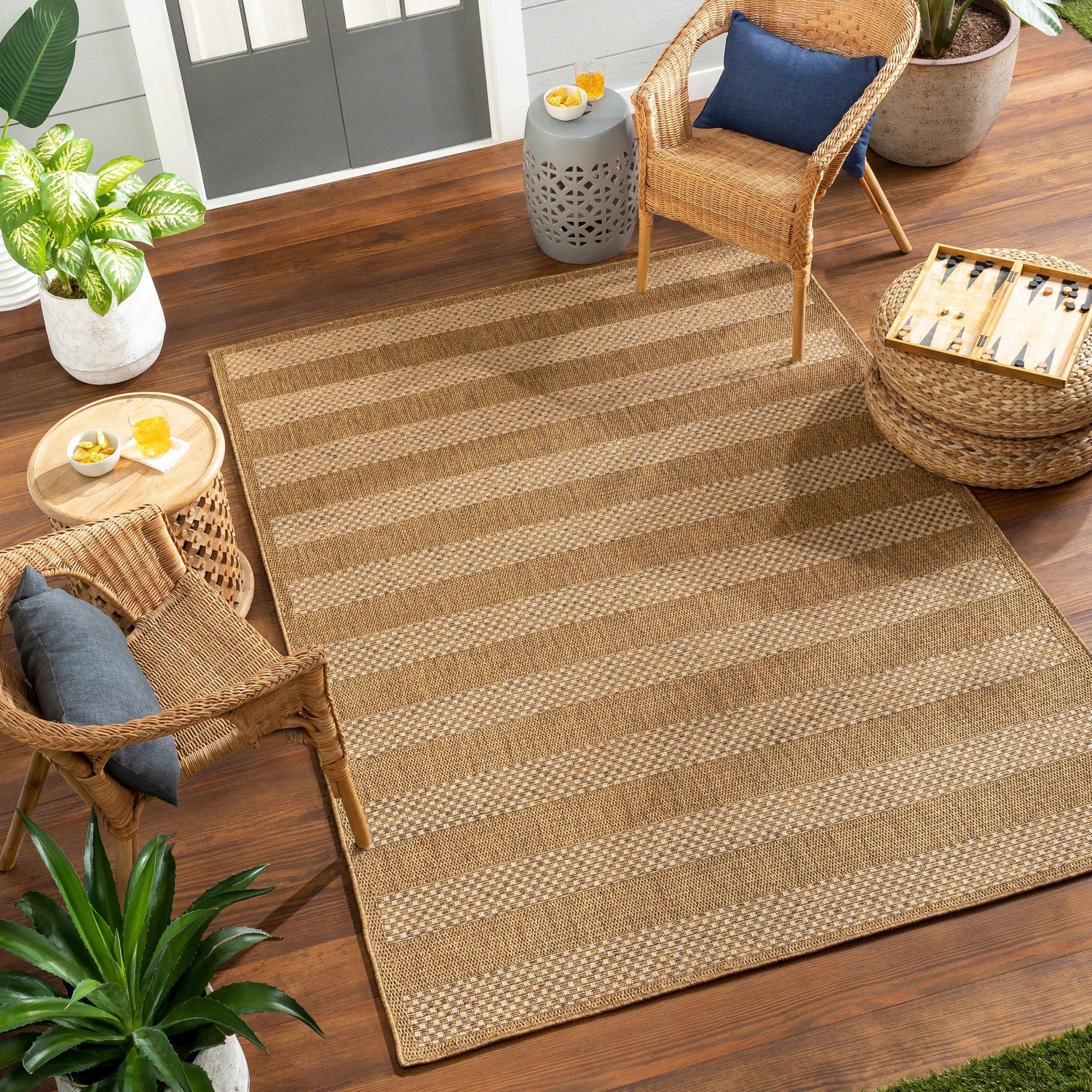Outdoor patio scene with Hiero Flatweave Faux Jute Rug in beige stripes, wicker chairs, and potted plants. Roomscene-Rectangle
