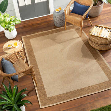Outdoor patio scene with Inigo Flatweave Faux Jute Rug in dark beige, wicker chairs, and potted plants. Roomscene-Rectangle