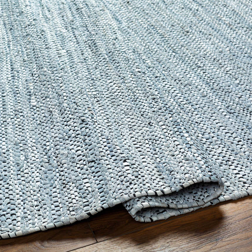 Close-up of the hand woven Aneko Cream Area Rug showing its arctic stone, gray, and black textured design. Fold