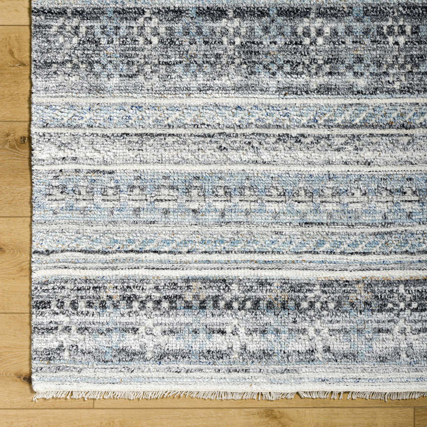 Close-up of the Blue Adda Area Rug showing its black, blue, and off-white Scandinavian-inspired pattern and hand-knotted texture. Corner