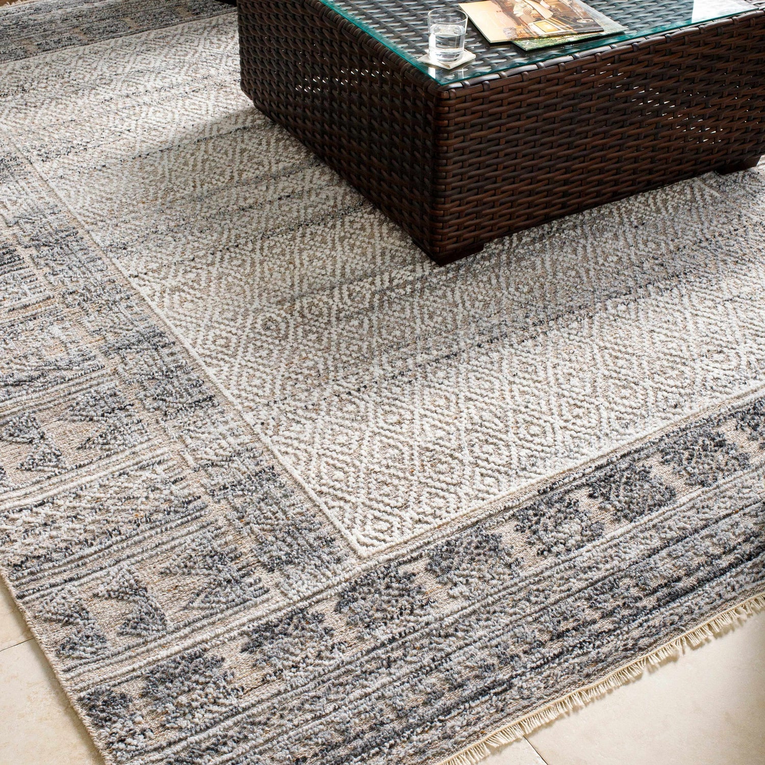 Close-up of the Betha Area Rug showing black, metallic silver, and olive tones with a geometric pattern and hand-knotted texture. Styleshot