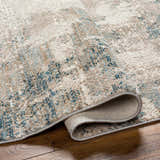 Close-up of the Funda Area Carpet, showing its abstract charcoal, brown, and seafoam pattern and soft, machine-woven texture. Fold