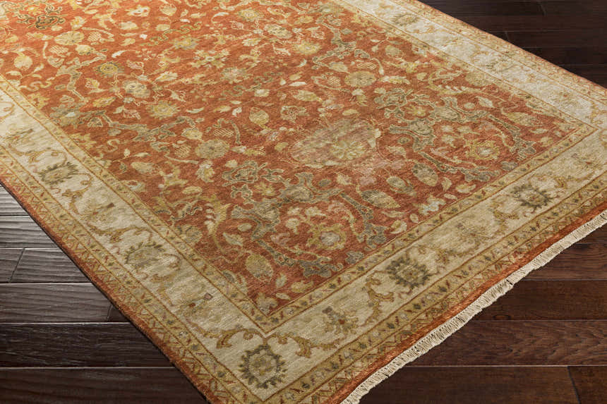 Close-up of the hand-knotted Springerville Area Carpet. Farmhouse style rug with traditional floral pattern in rust, gold, and cream. Corner