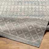 Close-up of Tambac Blue & Gray Washable Area Rug showing geometric pattern and soft texture on wood floor. Fold