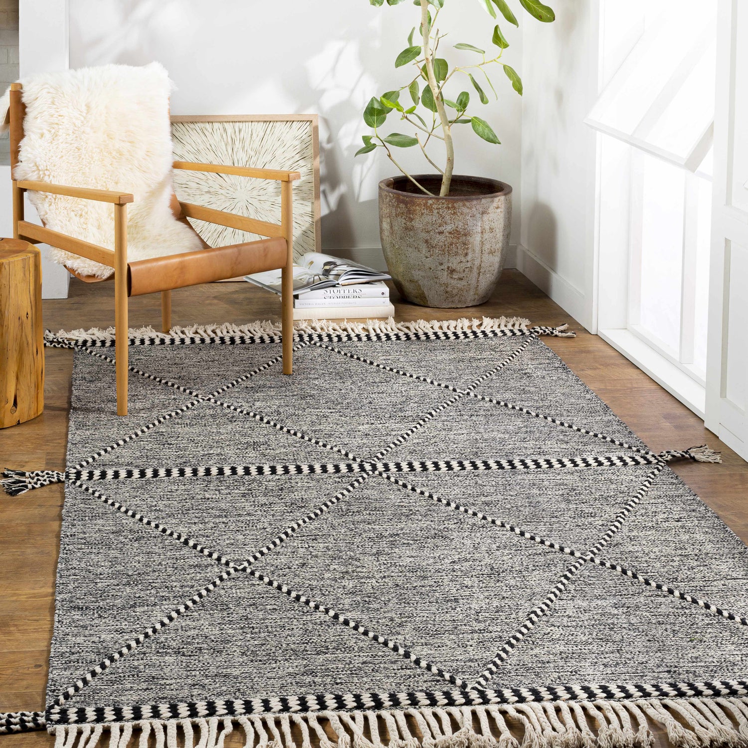 Bohemian-style room with a black and cream Spottswood Area Rug, wood chair, and potted plant. Roomscene-Rectangle