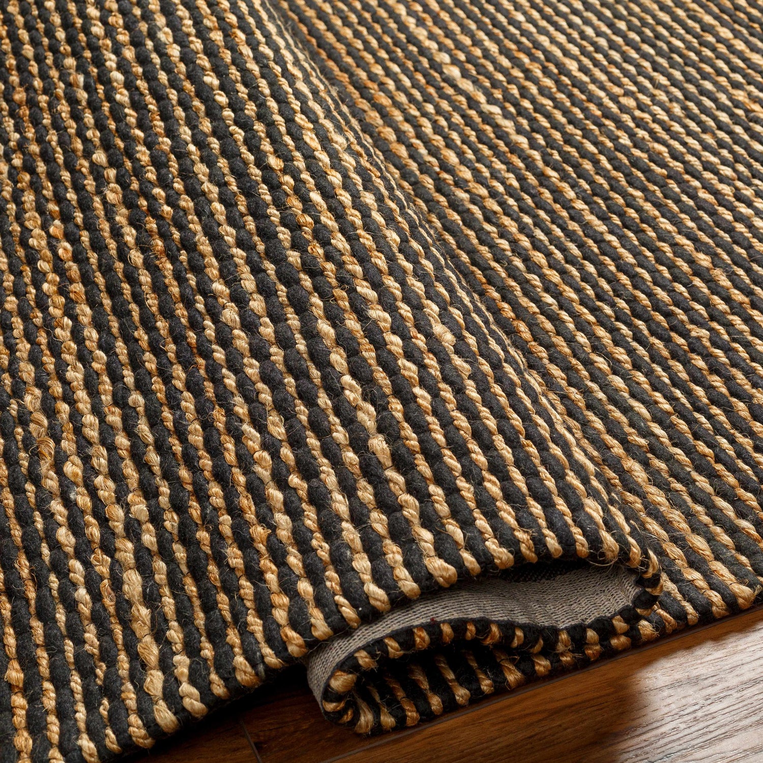 Close up of the hand woven Riki Black Area Rug showing jute texture and striped design. Fold