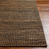 Close-up of the hand woven Riki Black Area Rug, showcasing its jute texture and contemporary black and tan design. Front