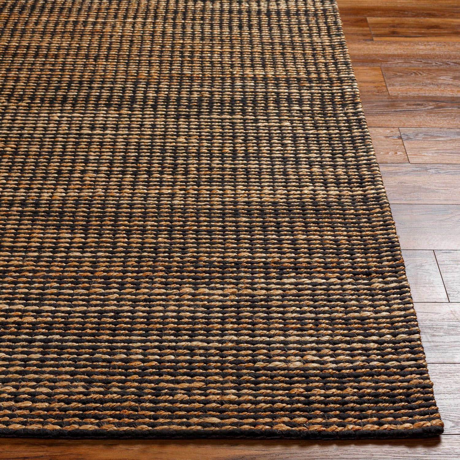 Close-up of the hand woven Riki Black Area Rug, showcasing its jute texture and contemporary black and tan design. Front
