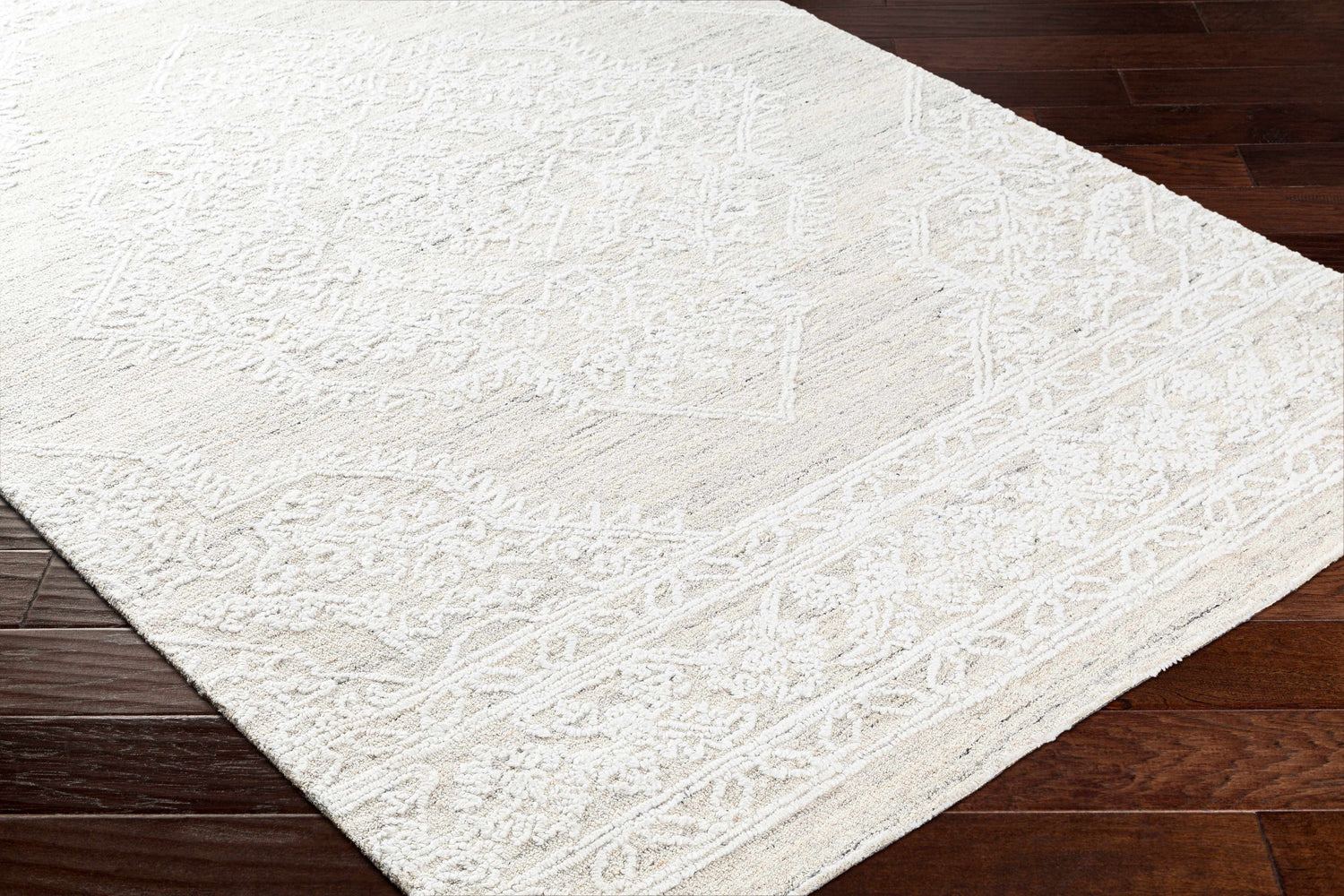 Close-up of the Denae Cream Area Rug showing its traditional pattern and hand-tufted texture on dark wood floors. Corner