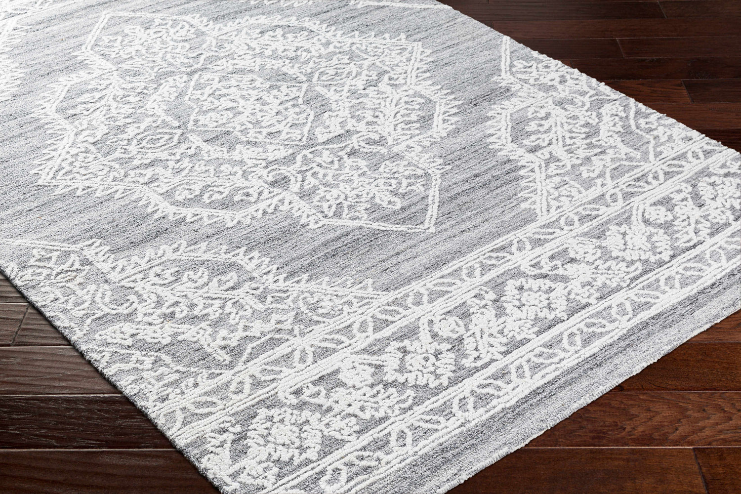 Close-up of the Denae Blue Area Rug showing the gray and white traditional floral pattern and hand-tufted texture. Corner