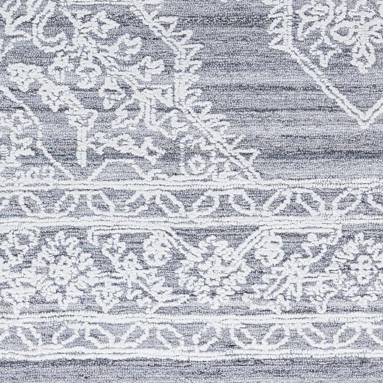 Close-up of the hand-tufted Denae Blue Area Rug, featuring a gray and white traditional floral pattern and textured recycled yarn. Swatch