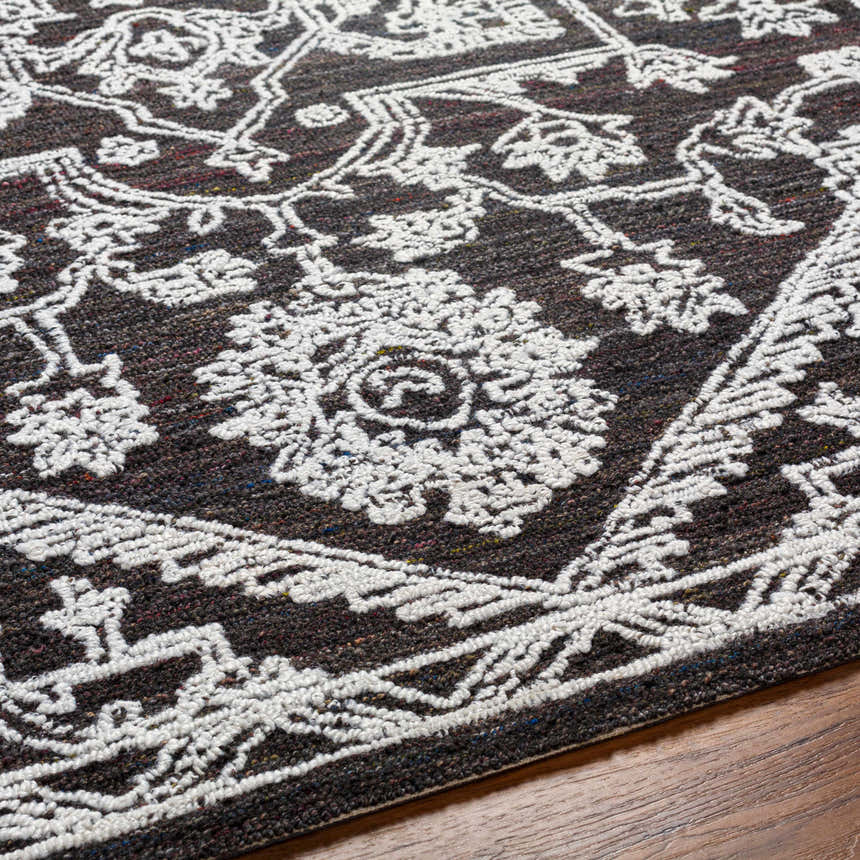 Close-up of the Black Derya Area Rug showing its charcoal color and traditional light gray floral pattern. Texture