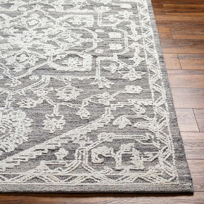 Close-up of the Blue Derya Area Rug showcasing its gray tones and traditional white floral pattern on a wood floor. Front