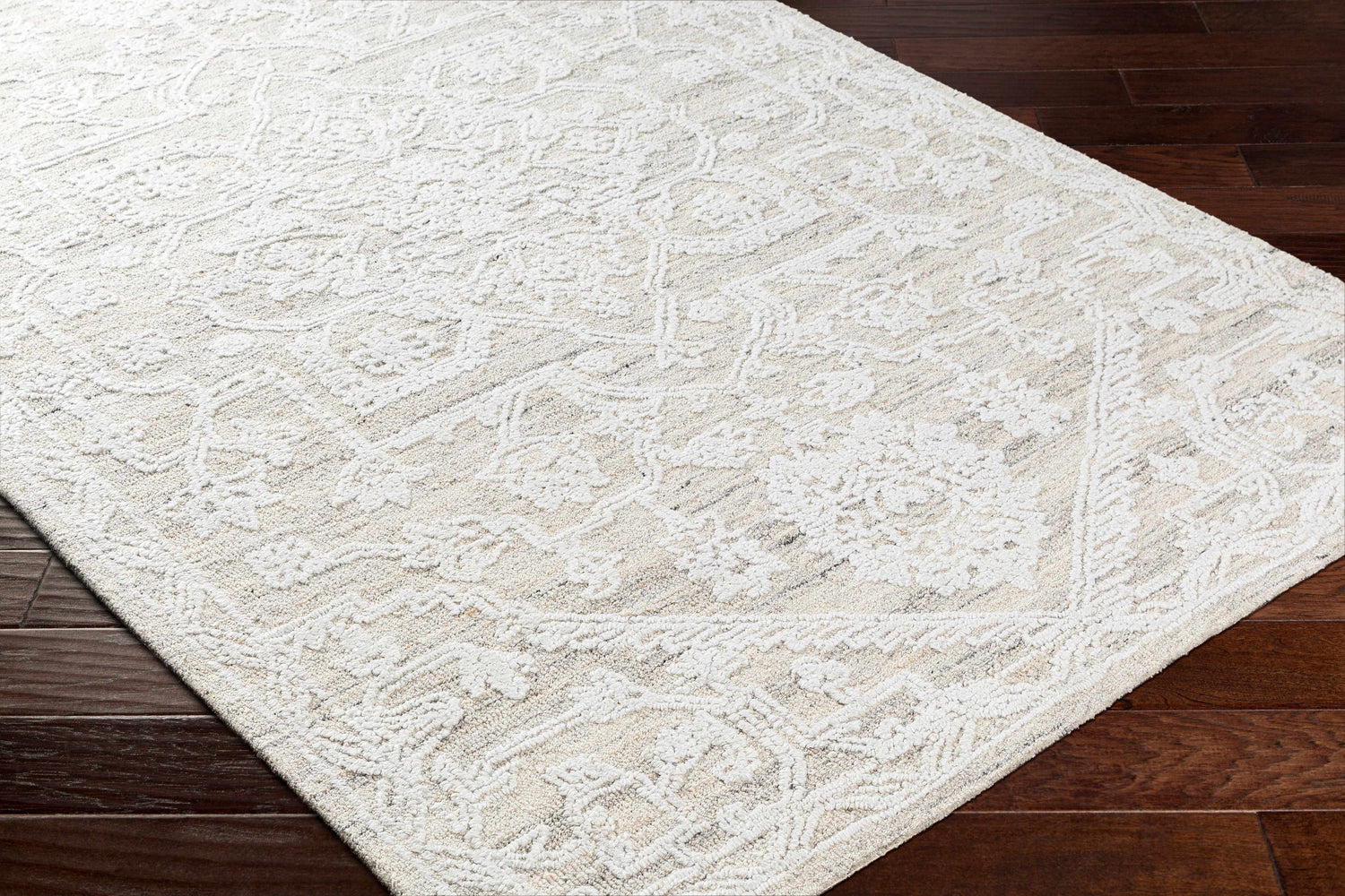 Close-up of the hand-tufted White Derya Area Rug showing its traditional floral pattern and soft texture on dark wood floors. Corner
