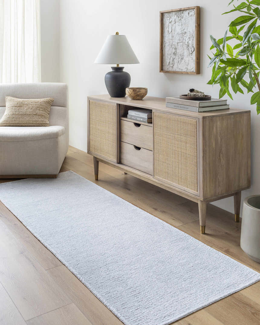 Living room scene with light blue Isako Washable Rug, wood floors, console table, chair, and natural light. Roomscene-Runner